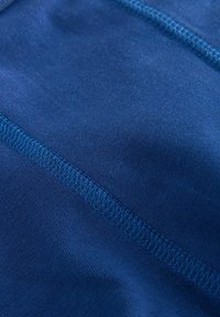 Navy blue tkanina o gładkiej fakturze z przeszyciem w turkusowym kolorze. Minimalne zagniecenia z zbliżeniem na detale tkaniny.