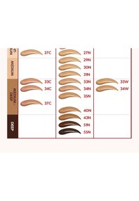 Swatches of foundation in various skin tones arranged in rows. Colors range from light to deep, labeled with numeric codes for identification.