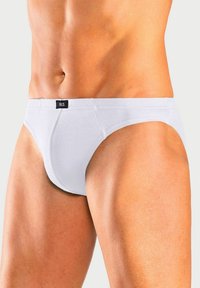 Weiße Baumwollslips mit einem taillierten Design, versehen mit einem schwarzen "H.I.S"-Label am Bund und einer glatten Textur.