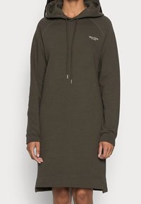 Huppari-mekko oliivinvihreänä, jossa on pitkät hihat, edessä kengurupocket, nyöritettävä huppu ja ribbireunus sivuleikkauksilla.