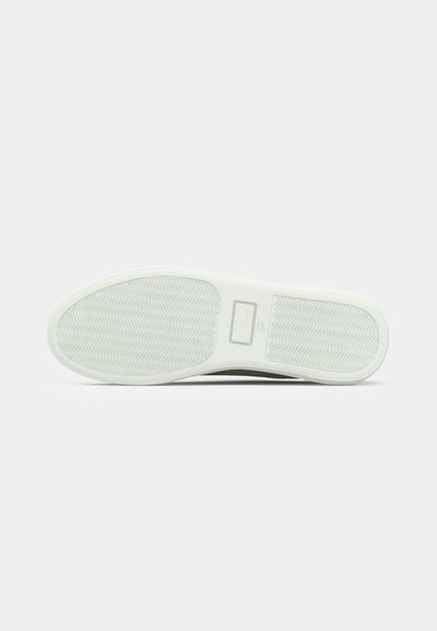 Λευκή σόλα παπουτσιού από καουτσούκ με ζιγκ-ζαγκ σχέδιο στο πέλμα και λεία επιφάνεια. Διαθέτει ορθογώνιο χώρο με σήμανση κοντά στην καμάρα.