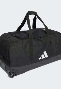 Sac de sport noir en tissu texturé. Équipé de roues, de poignées solides, d'une fermeture éclair sur le dessus et d'un accent logo blanc sur le côté.