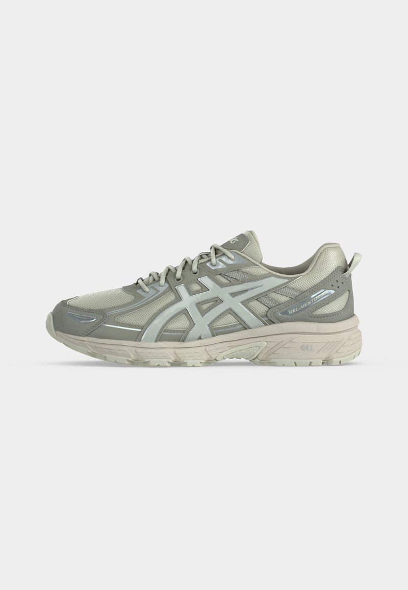 Zapatilla deportiva de color gris claro con parte superior de malla, cierre de cordones, suela acolchada y logotipo de marca en el lateral, vista de perfil sobre fondo blanco.