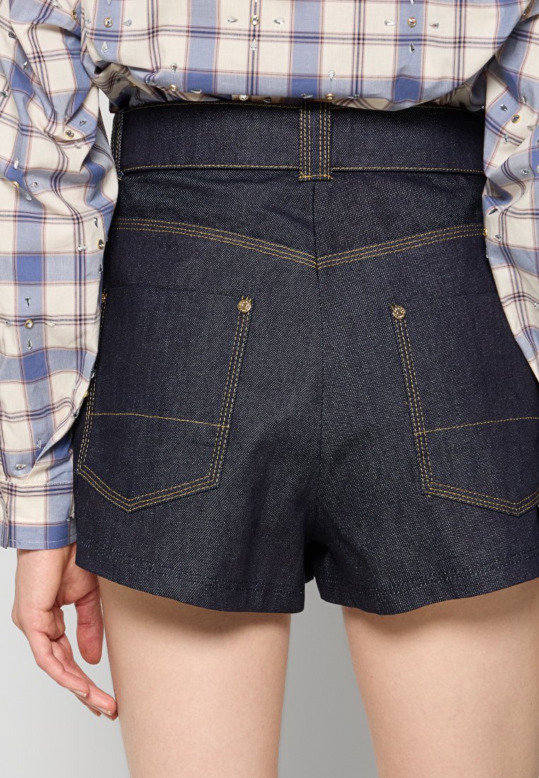Pantalones cortos de mezclilla en color azul marino oscuro con una cintura alta, con costuras en contraste, dos bolsillos traseros y una textura suave.