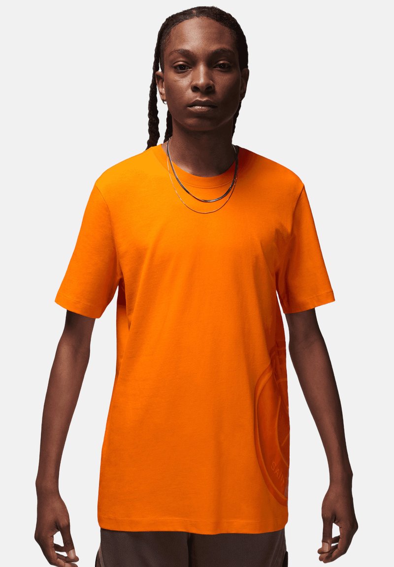 T-shirt a maniche corte in cotone arancione brillante con una vestibilità morbida, dotata di un collo rotondo e un discreto dettaglio del logo sulla parte anteriore.