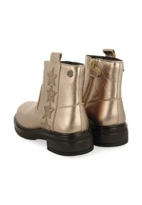 Stivaletti metallici oro con zip laterale, suola in gomma nera e cinque accentuazioni a forma di stella glitterate su un lato. Texture liscia.