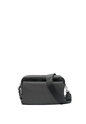 Kompaktowa czarna torba na ramię z regulowanym paskiem, przednią kieszenią, górnym zamkiem błyskawicznym i srebrnymi elementami na białym tle.