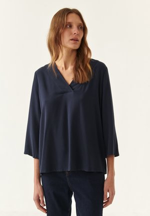 Marineblaue, semi-elegante Langarmbluse mit V-Ausschnitt. Weicher Stoff, leichtes Material, fällt bis zur Hüfte und hat breite Ärmel.