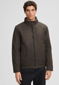 Dunkelgrüne gepolsterte Jacke mit hohem Kragen, Frontreißverschluss und seitlichen Taschen. Glatte Textur und lässiger Schnitt, geeignet für kältere Wetterbedingungen.