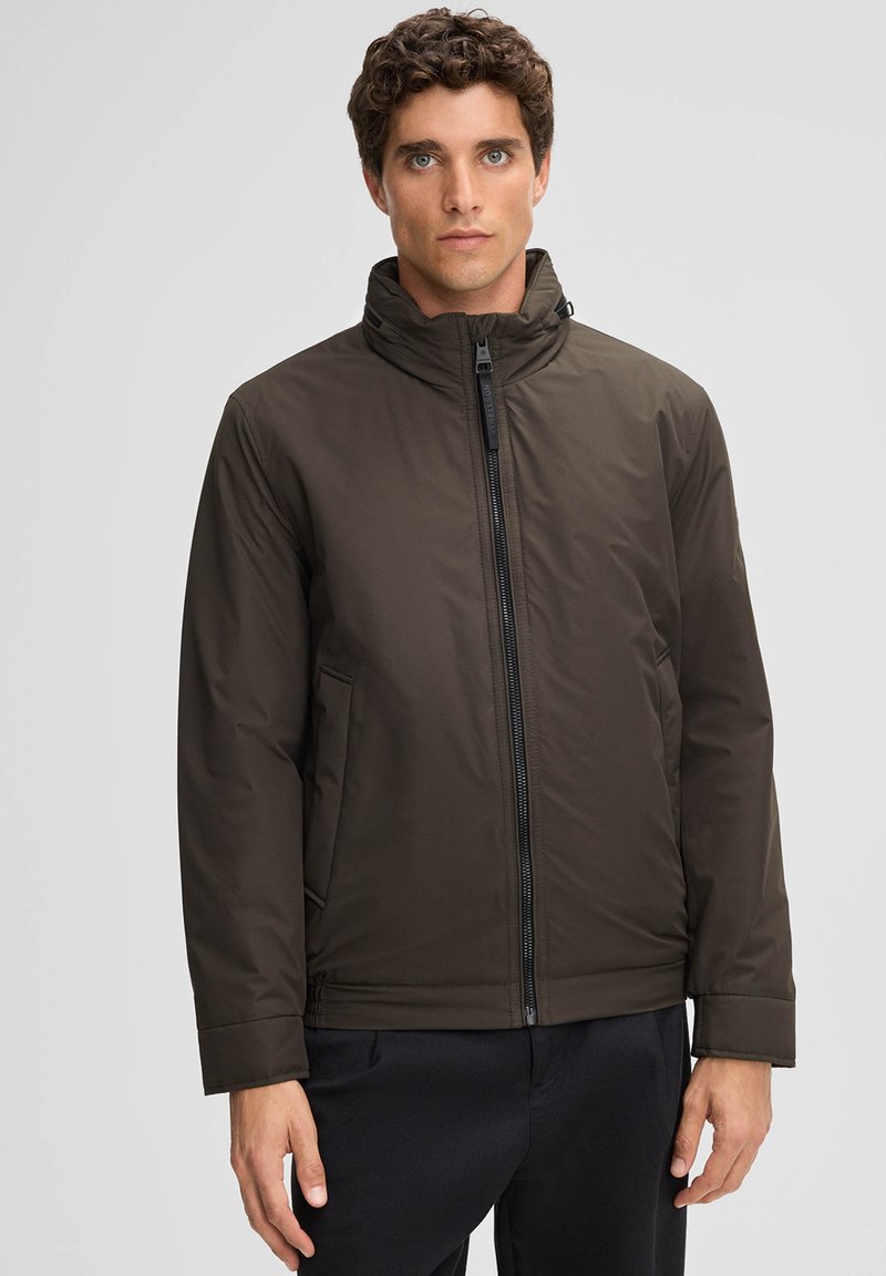Dunkelgrüne gepolsterte Jacke mit hohem Kragen, Frontreißverschluss und seitlichen Taschen. Glatte Textur und lässiger Schnitt, geeignet für kältere Wetterbedingungen.