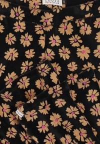 Zwarte stof met een bloemenpatroon van gouden bloemen met roze centra. Zachte textuur met een lichte glans, gelabeld met "LOOXS."