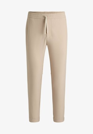 Pantaloni beige con vita elastica e cordino, gamba affusolata, tasche laterali e tessuto liscio e leggero. Design semplice senza motivi.