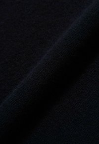 Tissu bleu marine foncé avec une surface douce et texturée, présentant un éclat subtil et un pli lisse et drapé. Idéal pour les vêtements ou les accessoires.