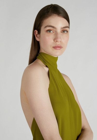Robe sans manches vert olive avec un col haut, en tissu lisse, présentant un corsage ajusté et un dos ouvert.