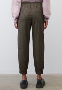 Bruine broek met streepjes, voorzien van een elastische tailleband, zijzak en smalle manchetten. Gemaakt van een gestructureerde stof.