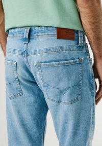 Vaaleansiniset denimit, joissa on rento istuvuus. Mukana on kaksi takataskua, kontrastiväriset saumat ja ruskea nahkapatch, joka korostaa brändiä.