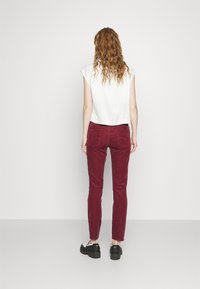 Rode corduroy broek met een slim fit en achterzakken, gecombineerd met een witte top met korte mouwen en zwarte platformschoenen.