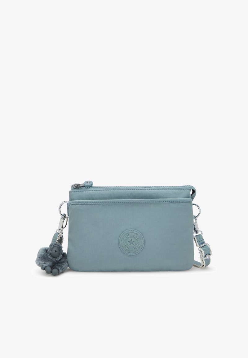 Blå stof crossbody taske med et rundt logo som accent, lynlås lukning og en dejlig abe nøglekæde. Har en justerbar rem til alsidig brug.