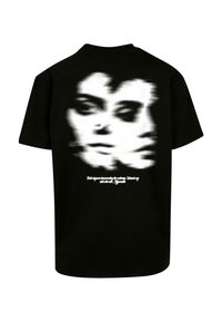 Sort bomulds T-shirt med et sløret, dobbelt ansigt grafiktryk på ryggen og hvid tekst nedenunder. Korte ærmer, crew neck design.