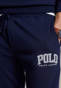 Mörkblå sweatpants i mjukt tyg, med en broderad "POLO RALPH LAUREN"-logotyp på låret och justerbart midjeband.