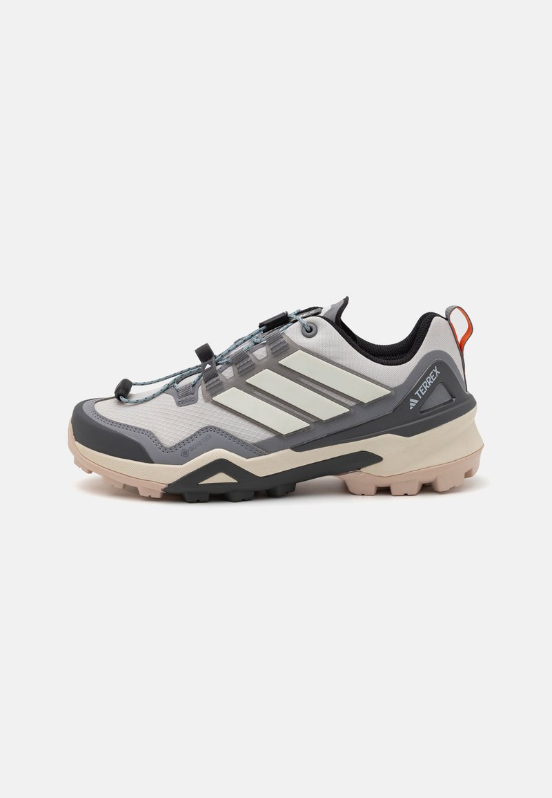 Sapatilha de trail running leve em cinza, com um upper texturizado, detalhes em preto e sola de borracha. Apresenta um sistema de atamento seguro e um calcanhar acolchoado.