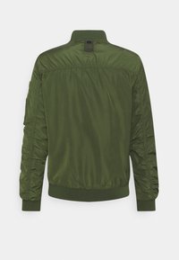 Oliwkowa kurtka typu bomber z gładkim, teksturowanym wykończeniem, ściągaczami przy mankietach i u dołu, marszczonymi panelami bocznymi oraz pętelką z metką z tyłu.