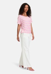 Lyserød og hvid stribet kortærmet top parret med hvide vide bukser og lyserøde hælede sandaler. Stoffet virker blødt og let.