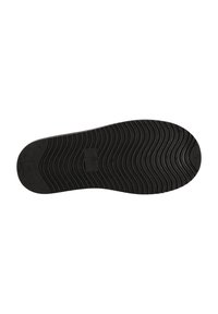 Semelle de chaussure en caoutchouc noir avec une texture ondulée, des motifs de semelle circulaires et une plaque rectangulaire près du talon pour une meilleure adhérence.