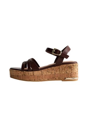 Sandalo marrone in pelle con cinturini, fibbia regolabile e zeppa in sughero con accento metallico alla base.