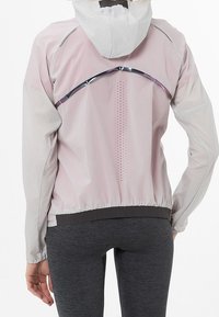 Chaqueta liviana con capucha en rosa y blanco, con detalles reflectantes, paneles de malla y dobladillo elástico, diseñada para flexibilidad y transpirabilidad.