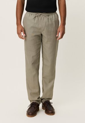 Lys khaki linbukser med snor i midjen, rett snitt og subtil tekstur, kombinert med mørkebrune sko.