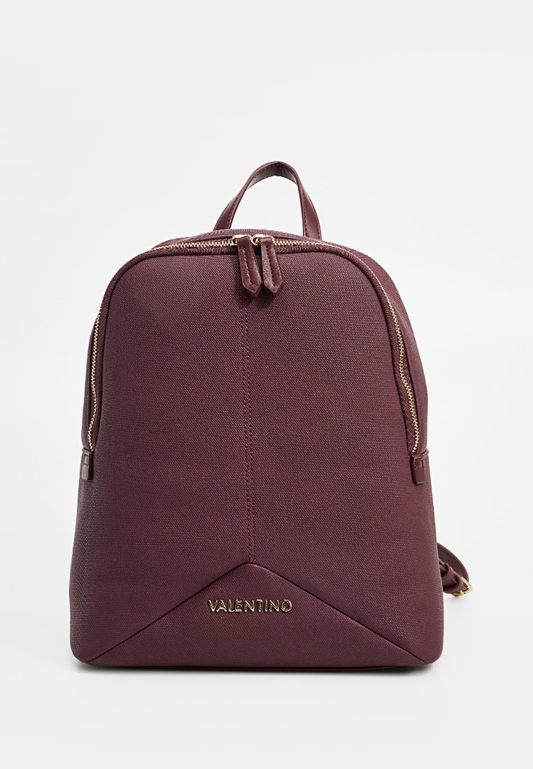 Burgunderfarget lær ryggsekk med en glatt tekstur, doble glidelåser og en gullpreging av logoen nederst. Kompakt, rund form.