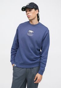 Sweatshirt azul marinho com decote redondo e logótipo bordado de urso. Material de mistura de algodão, punhos e bainha canelados, corte descontraído.