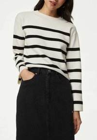 Pull en tricot crème avec des rayures noires, col rond et manches longues. Assorti avec une jupe en denim noire taille haute, dotée de poches.