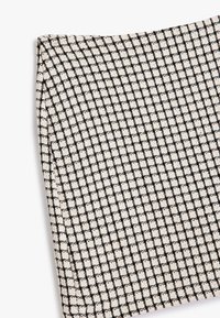 Textiel met een zwart-wit ruitpatroon, met een iets ruwe oppervlakte. Het materiaal is geweven en heeft een kenmerkend ruitontwerp.