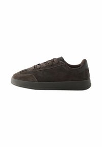 Brązowe zamszowe sneakersy z sznurowaniem i czarną gumową podeszwą, pokazane z boku na białym tle.