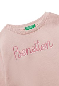 Maglione rosa chiaro con scollatura a coste, con la scritta "Benetton" in lettering rosa lucido. L'etichetta recita "United Colors of Benetton."
