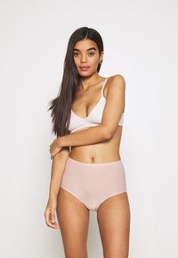 Light pink bralette with a ribbed texture and adjustable straps, paired with high-waisted, smooth, light pink briefs.