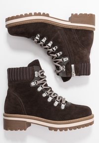Brązowe zamszowe botki za kostkę z żebrowanym kołnierzem, metalowymi oczkami, sznurowanym przodem, bocznym zamkiem błyskawicznym oraz teksturowaną gumową podeszwą.