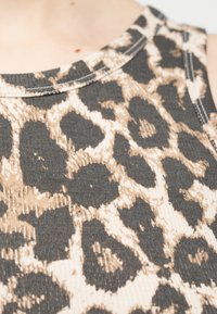 Κοντινή λήψη ενός τοπ από ριμπ ύφασμα με καφέ και μαύρο μοτίβο λεοπάρ και ορατή ραφή στη λαιμόκοψη.