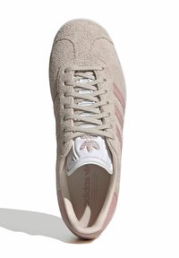 Bežīgas zamšādas tenisa kurpes ar rozā svītrām, strukturēta virsma, baltas auklas un balta mēle ar logotipu, apaļa purngala forma un elastīga zole.