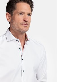 Witte button-up shirt met een colarfase met bloemenpatroon en zwarte knopen, met een klassieke pasvorm en een zachte textuur.