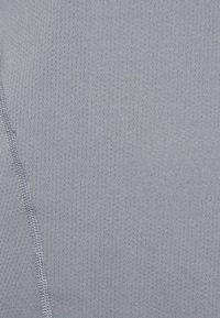 Tissu athlétique gris clair présentant un motif texturé avec de petites perforations et des coutures plates pour un aspect épuré.