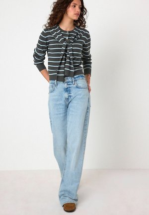 Grå och blå randig cardigan med knyte framtill, i kombination med ljusblåvida jeans. Strukturerad tyg, mjukt utförande och avslappnad stil.