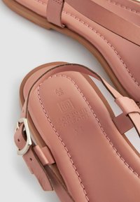 Rosa Leder-Sandalen mit flacher Sohle, mehreren Riemen, einer dekorativen Naht und einer silbernen Schnalle für eine verstellbare Passform.