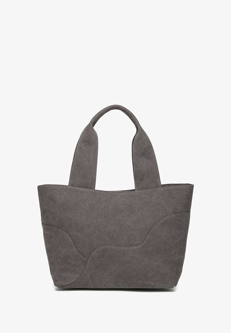 Sac fourre-tout en tissu gris avec surface texturée, deux poignées courtes et un design doux et incurvé. Extérieur uni sans quincaillerie visible.