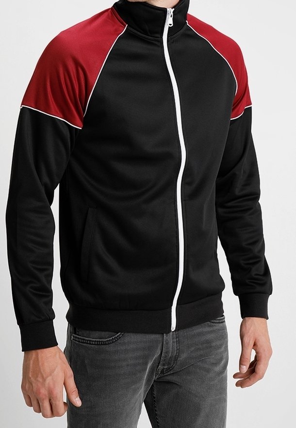 Giacca nera con zip, spalle rosse, piping bianco e due tasche laterali. Realizzata in tessuto liscio e elasticizzato.