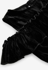 Top en velours noir avec des manches à volants et une texture lisse et douce. Le design comprend un corsage ajusté et un col ras du cou.