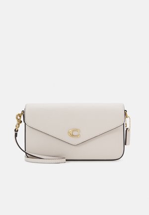 White leather wristlet clutch with gold hardware, front flap closure, and a small gold logo emblem in center.