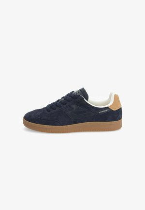Navy suede sneaker with a rubber gum sole, black leather accents, round toe, and flat laces. White lining and branding on the side.